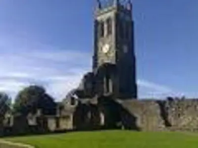 a clock tower on top of a building with a green field at Nethermains House in Kilwinning