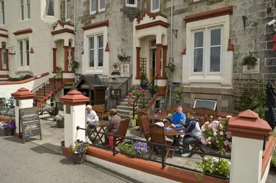 a group of people sitting at a table outside of a building at Corran House Guest House in Oban
