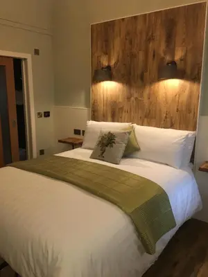 a bedroom with a large white bed with a wooden headboard at Rosemount Boutique B&B in Lanark