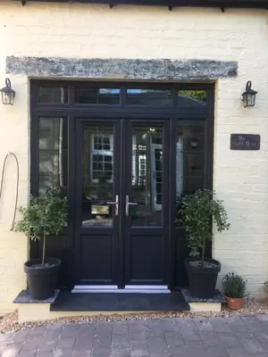 a black door on a building with two potted plants at Rosemount Boutique B&B in Lanark