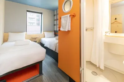 a small room with two beds and a sink at easyHotel Glasgow City in Glasgow