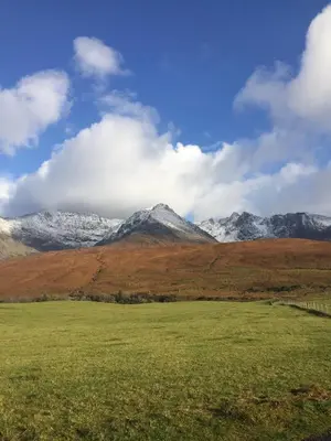 a field with snow capped mountains in the background at Tyndrum Lodges in Tyndrum