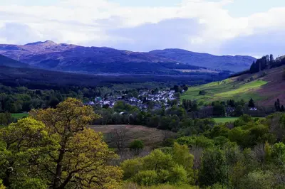 a view of a valley with a town and mountains at Waterfall Lodge - private waterfall and sauna in Killin