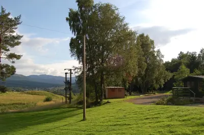 a field of grass with a telephone pole and a road at Waterfall Lodge - private waterfall and sauna in Killin