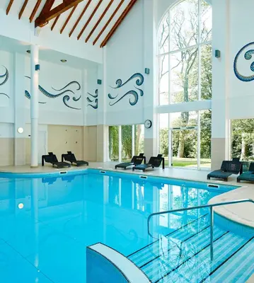 a swimming pool with blue water in a building at Dalmahoy Hotel & Country Club in Edinburgh