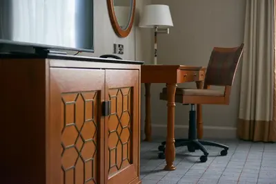 a desk with a television and a chair in a room at Dalmahoy Hotel & Country Club in Edinburgh