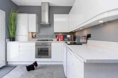 a black dog sitting on the floor in a kitchen at Crewe Apartment - Stylish 2 bedroom apt, Garden, Free parking, Edin City in Edinburgh