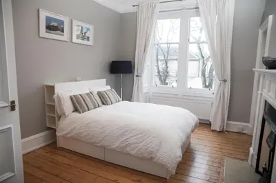 a white bedroom with a bed and a window at Edinburgh, Stockbridge Apartment in Edinburgh