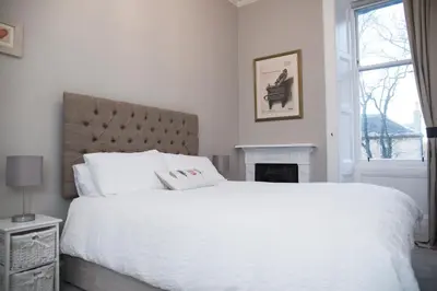 a white bedroom with a large bed and a fireplace at Edinburgh, Stockbridge Apartment in Edinburgh
