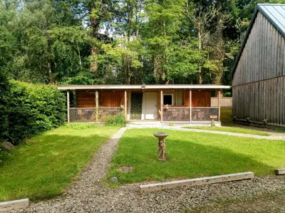 a house with a yard with a birdbath in front of it at Birchwood Guest Lodge in Balmaha