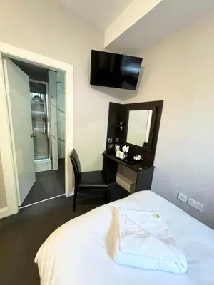 a bedroom with a bed and a mirror and a chair at Murrayfield Park Guest House in Edinburgh