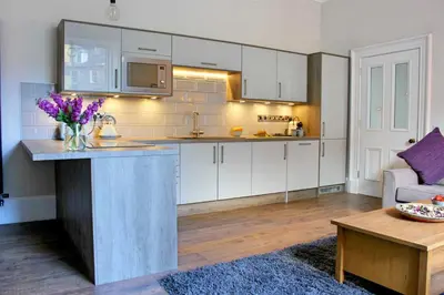 a kitchen with white cabinets and a table in a room at Kirk View Apartment in Stirling
