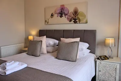a bedroom with a bed with white sheets and purple flowers at Kirk View Apartment in Stirling