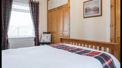 a bedroom with a bed and a window at Pippin, Tranquil Scottish Cottage with Hot Tub in Airdrie