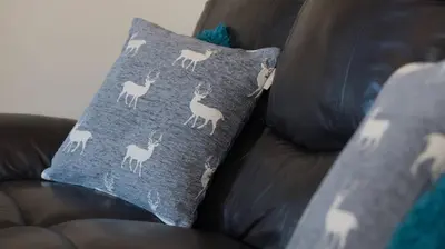 a pillow with llamas on it sitting on a couch at Pippin, Tranquil Scottish Cottage with Hot Tub in Airdrie