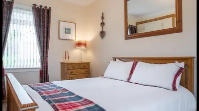 a bedroom with a bed and a mirror on the wall at Pippin, Tranquil Scottish Cottage with Hot Tub in Airdrie