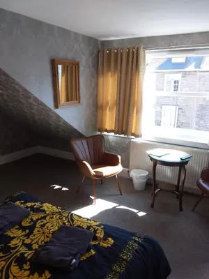 a bedroom with a bed and a chair and a window at IVY- Braveheart Guest House in Edinburgh