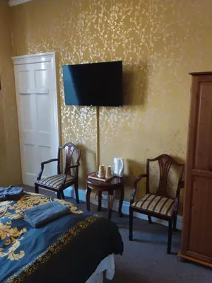 a hotel room with a bed and two chairs and a tv at IVY- Braveheart Guest House in Edinburgh