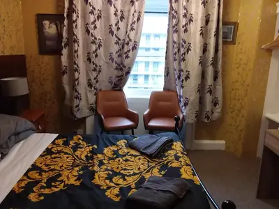 a bedroom with two chairs and a bed and a window at IVY- Braveheart Guest House in Edinburgh