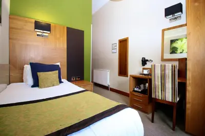 a bedroom with a bed and a wooden headboard at Acorn Hotel in Glasgow
