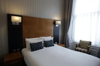 a hotel room with a large bed and a chair at Acorn Hotel in Glasgow