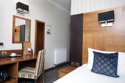a hotel room with a bed and a desk and a mirror at Acorn Hotel in Glasgow