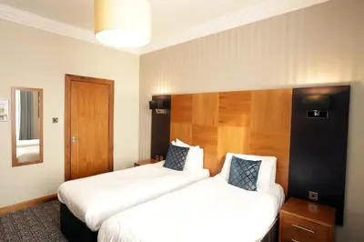 a hotel room with two beds and a mirror at Acorn Hotel in Glasgow