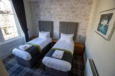 two beds in a small room with two windows at The Waverley Hotel in Callander