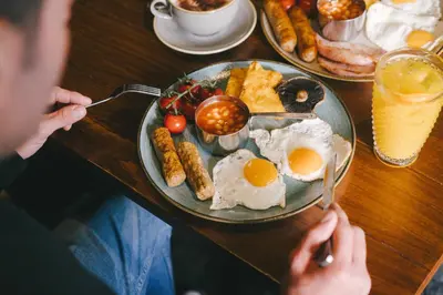 a person sitting at a table with a plate of breakfast food at The Waverley Hotel in Callander