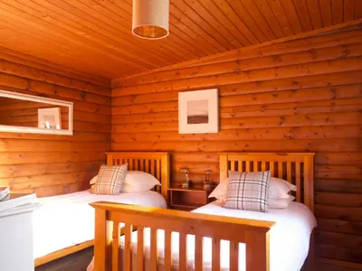 a bedroom with two beds in a log cabin at Hillside Log cabin, Ardoch Lodge, Strathyre in Strathyre