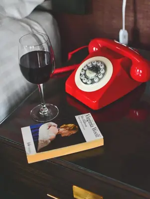 a red phone and a book and a glass of wine at The Rutland Hotel & Apartments in Edinburgh