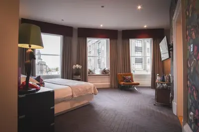 a hotel room with a bed and two windows at The Rutland Hotel & Apartments in Edinburgh