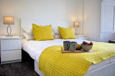 a bed with yellow pillows and a tray with fruit on it at Wallace View Apartment in Stirling