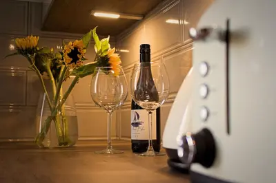 a bottle of wine and two glasses on a table at Wallace View Apartment in Stirling