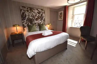 a bedroom with a large bed and a window at Elphinstone Hotel in Biggar