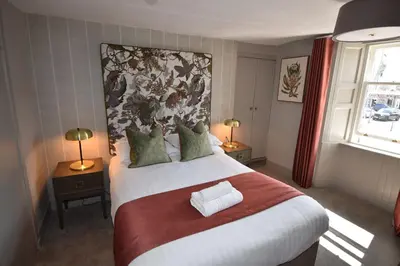 a bedroom with a large bed with a floral headboard at Elphinstone Hotel in Biggar