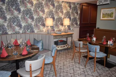 a dining room with tables and chairs and a wall at Elphinstone Hotel in Biggar