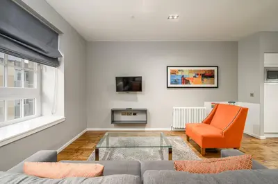 a living room with a couch and an orange chair at Destiny Scotland -The Malt House Apartments in Edinburgh