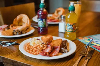 a table with plates of breakfast food and drinks at Toby Carvery Strathclyde, M74 J6 by Innkeeper's Collection in Motherwell