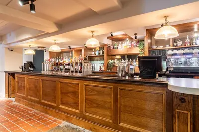 a bar at a restaurant with wooden cabinets at The Hawes Inn by Innkeeper's Collection in Queensferry