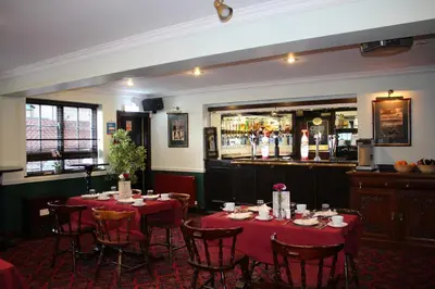 a dining room with tables and chairs and a bar at Ardmillan Hotel in Edinburgh