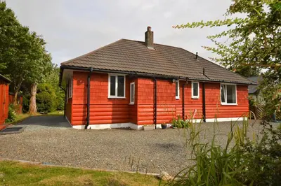 a small red house with a gravel driveway at Cedar Cottage in Dunoon
