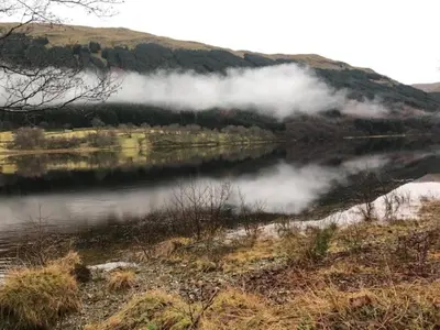 a view of a lake with clouds in the water at Woodside Logcabin Ardoch Lodge in Strathyre