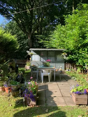 a patio with a table and flowers in a garden at Lowood Cottage in Edinburgh