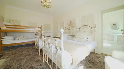 a white bedroom with two beds and a tub at The Old Tramhouse Self Catering Apartments in Stirling