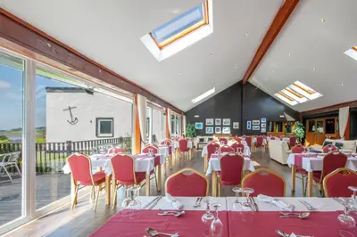a dining room with white tables and red chairs at The Galley Of Lorne Inn in Ardfern