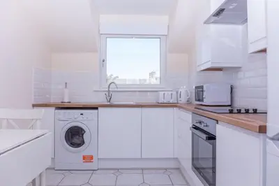 a white kitchen with a washing machine and a window at Ailsa Retreat in Troon