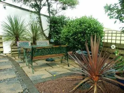 a garden with a bench and a table and plants at Ashbank Hotel in Carradale
