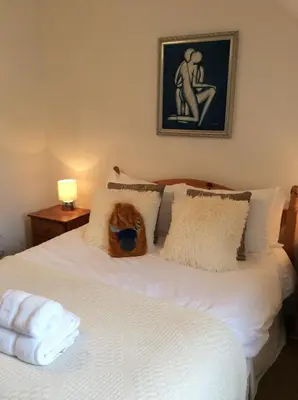 a cat sitting on top of a white bed at Ashbank Hotel in Carradale