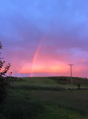 a rainbow in the sky over a field at Ashbank Hotel in Carradale
